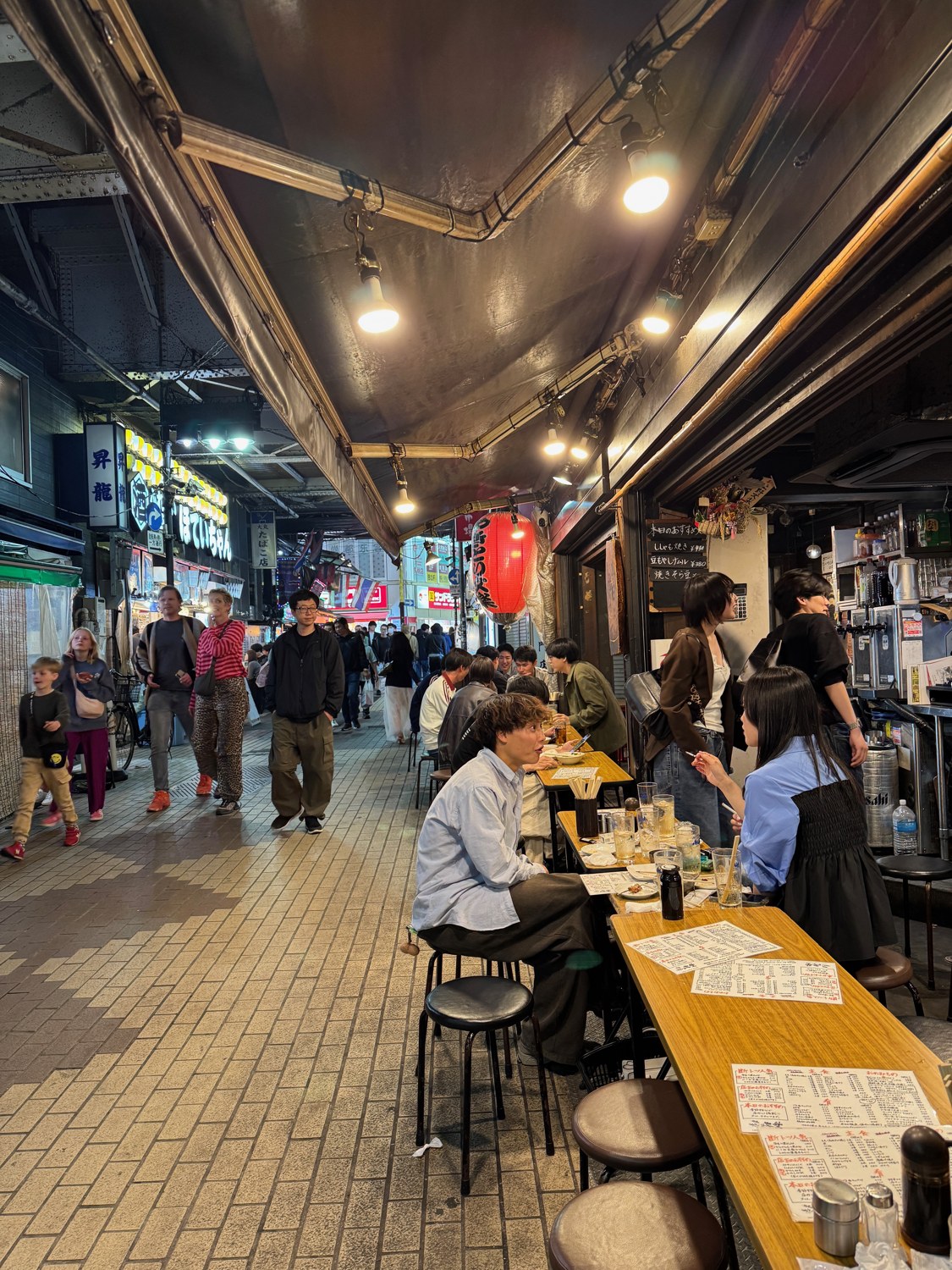 Überdachte Abendstraße in Japan mit Lampen und Tischen